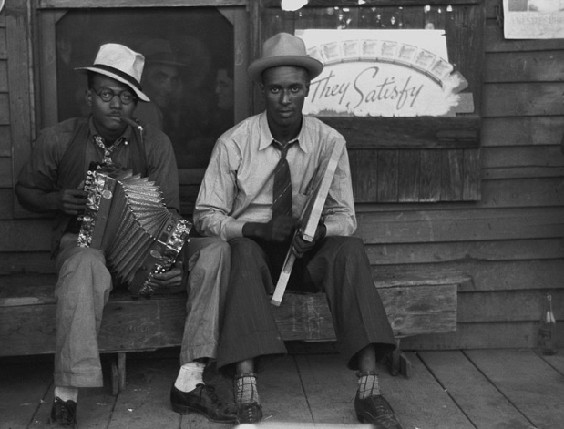Creole musicians playing accordion and washboard in front of store, near New Iberia, Louisiana in 1938.